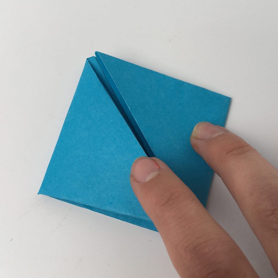 fingers folding origami paper for an origami cube