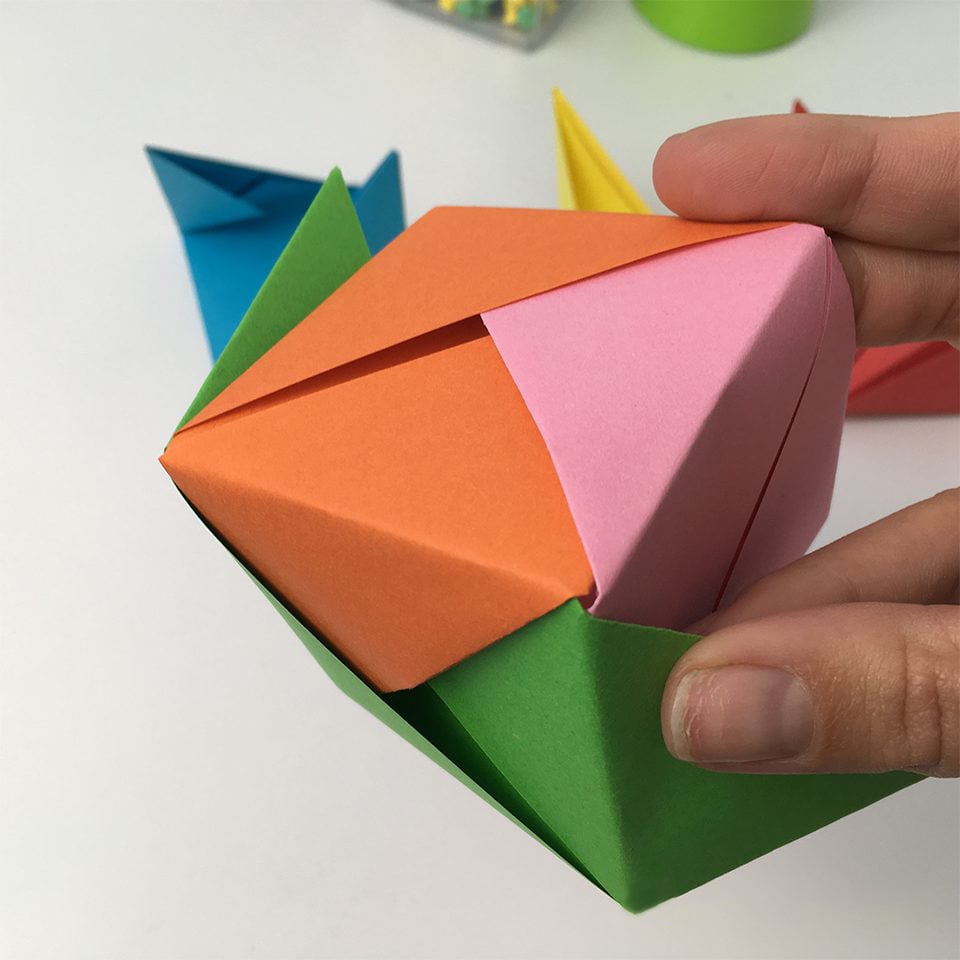 hands putting together origami box