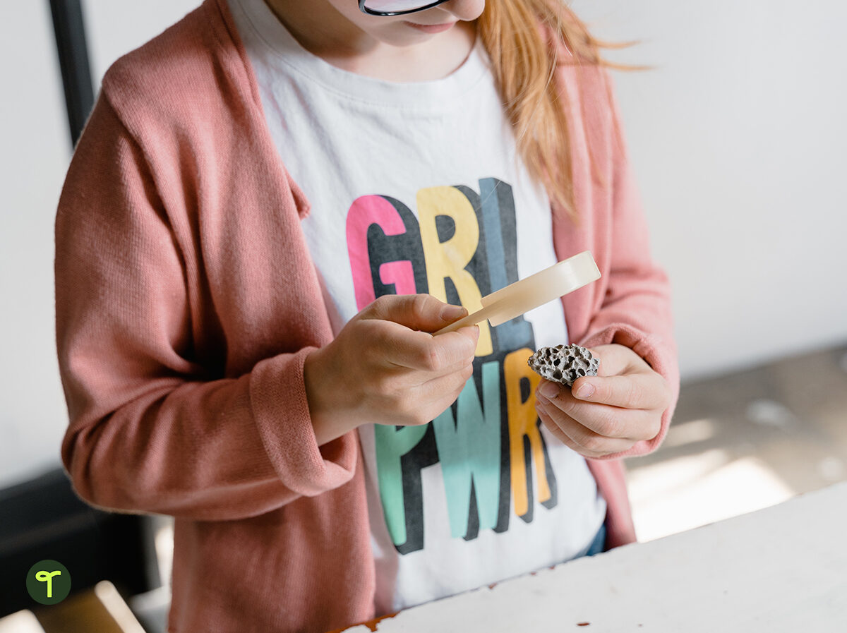 girl student in science class using a magnifying glass