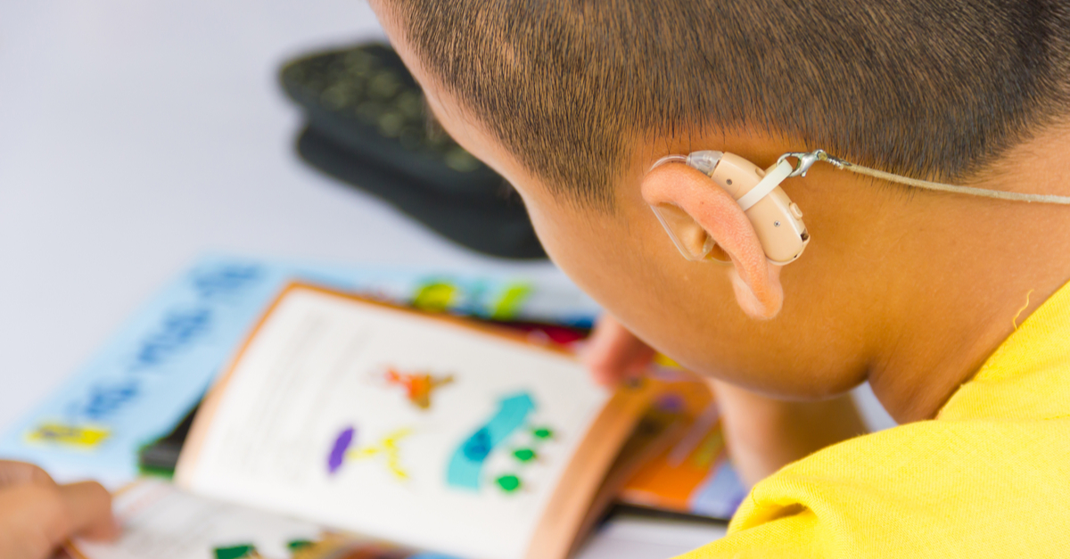 Boy with Hearing Aid looking at a Book