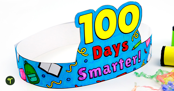 A kid's 100 days of school hat sits on a white table with paper streamers beside it