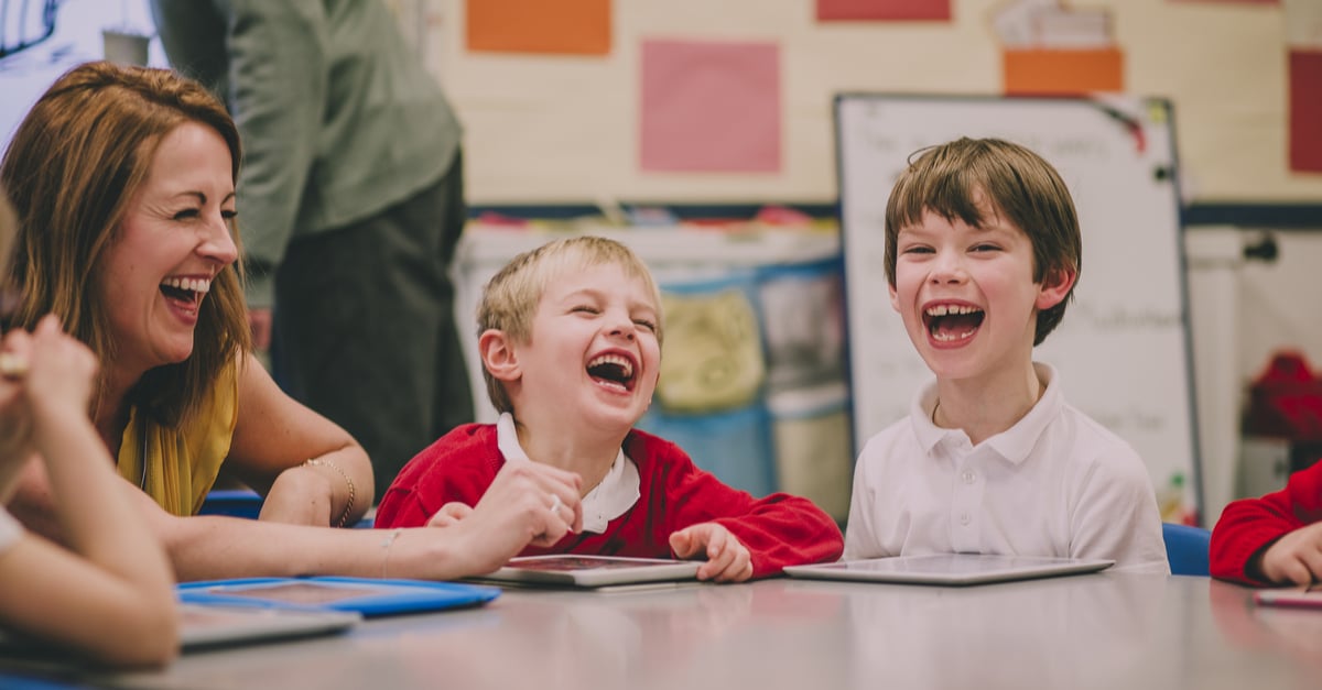 kids laughing with their teacher in the classroom