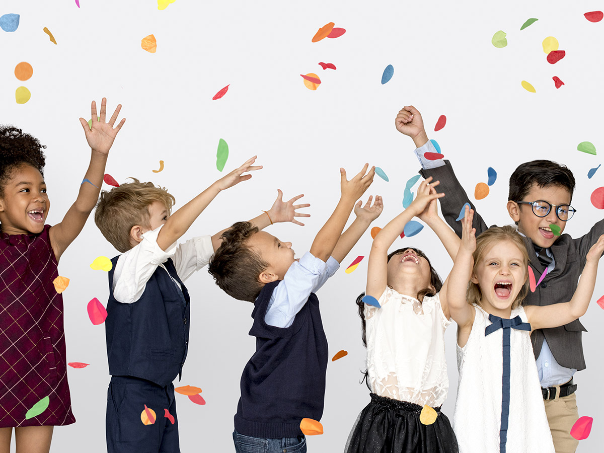  A group of diverse elementary school students are throwing colorful confetti in the air while celebrating their success in the classroom.