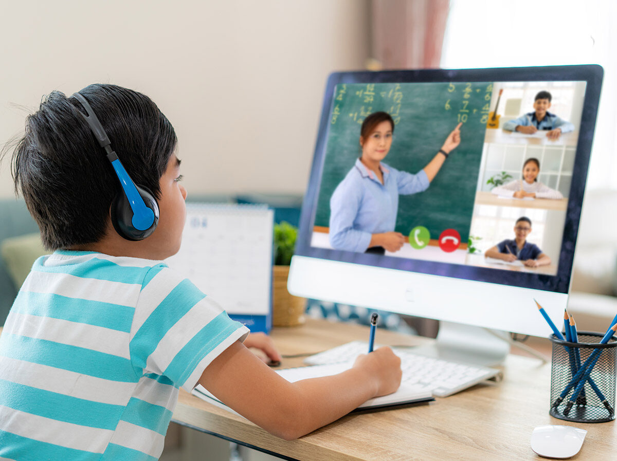 Child doing remote learning with teacher on screen