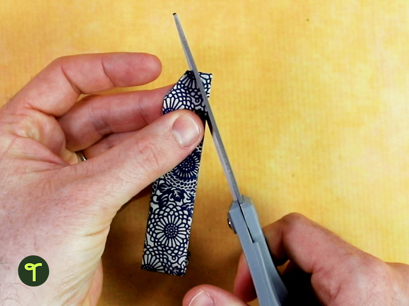 hands cutting piece of origami paper