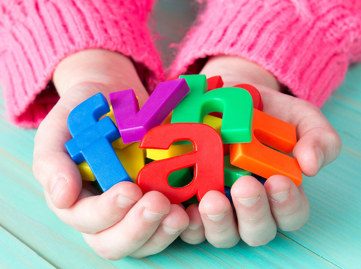Child holding magnetic letters in their hand