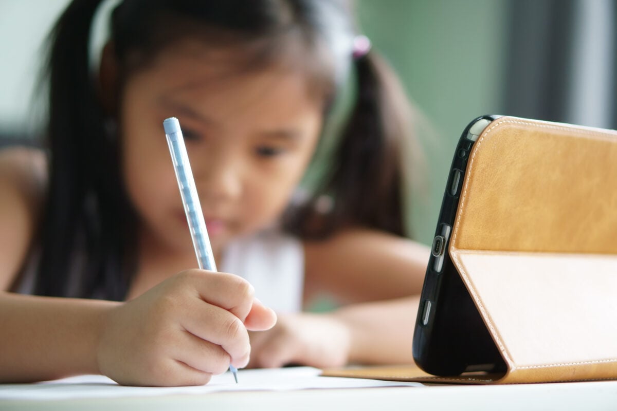 little girl using a pencil in a classroom