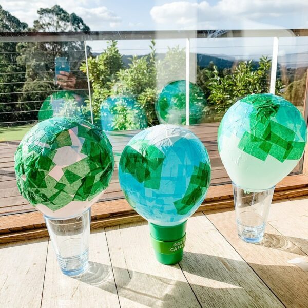 Three homemade Earth Day lanterns made of glasses, balloons and shredded tissue paper.