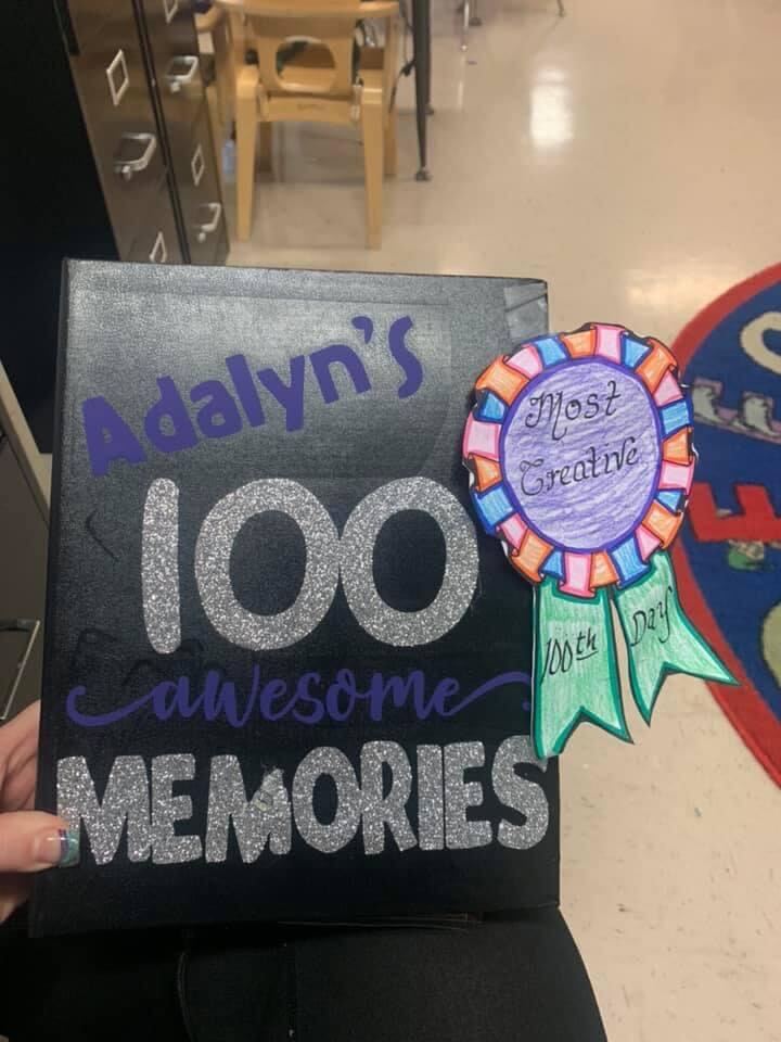 a student holds a 100 memories book created for the 100th Day of School