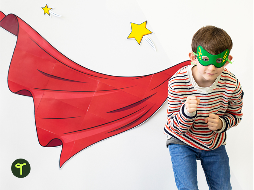 student poses as superhero with printable superhero classroom decoration