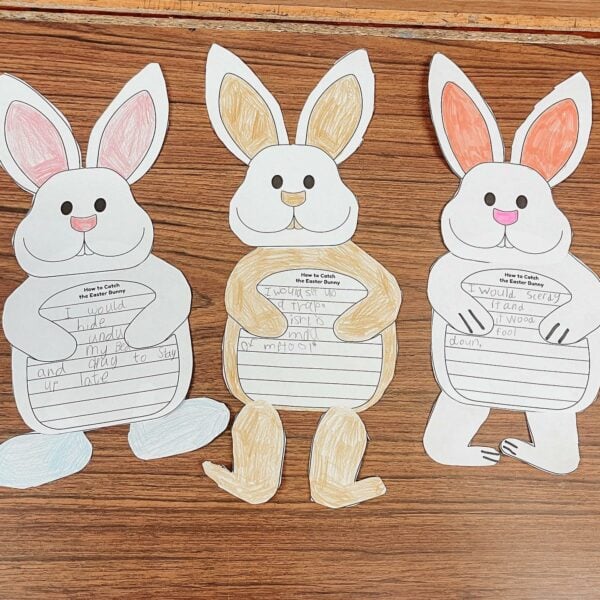 Paper Easter bunnies with writing on their bellies on a wooden table