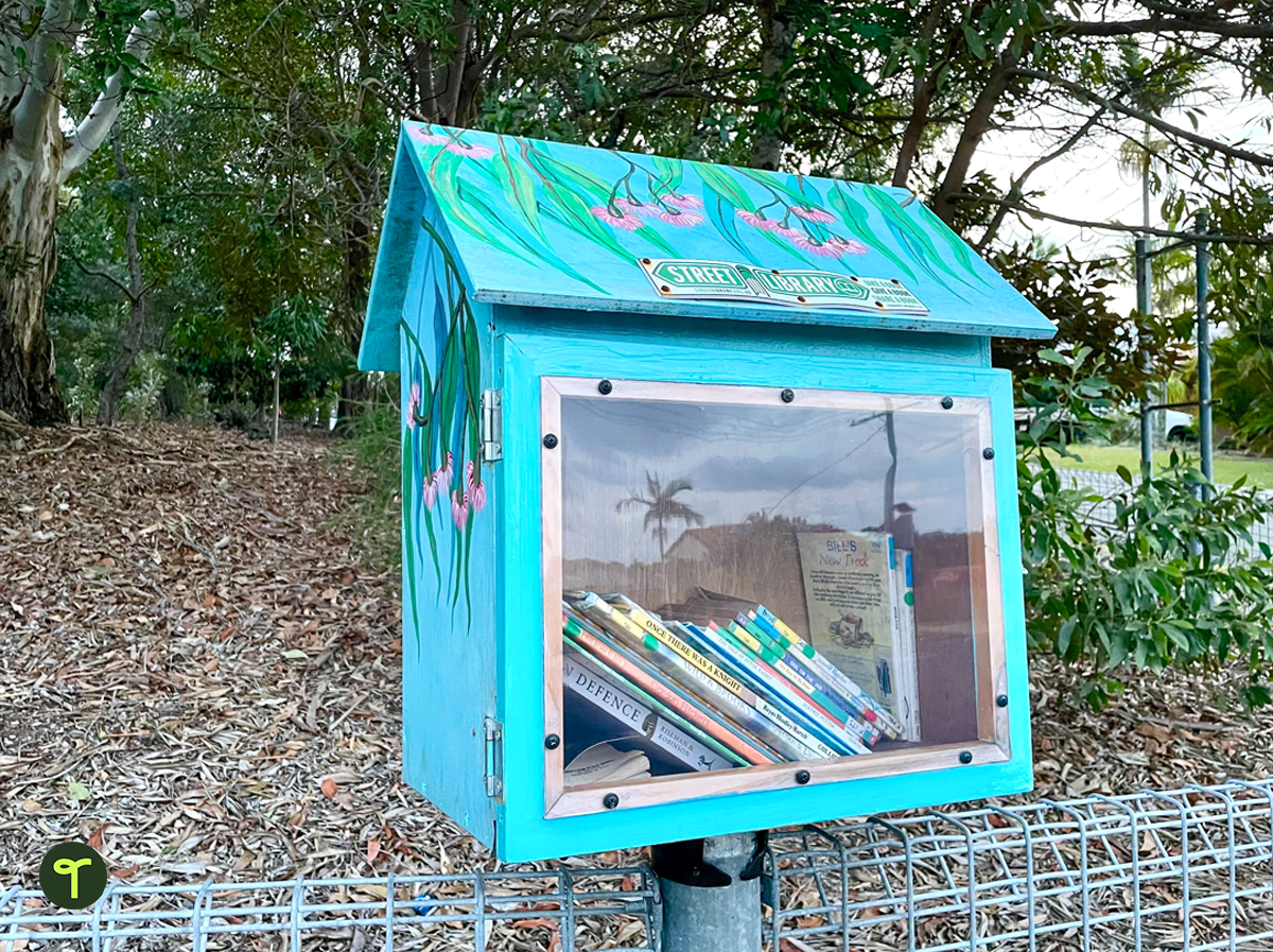 A blue box with painted pink wattle flowers full of kids library books