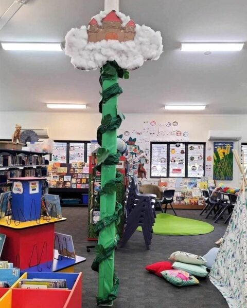 A pole in a library decorated with vines and cardboard castle at the top