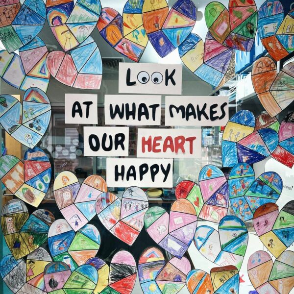Coloured in hearts on a window with the text 'Look at what makes our heart happy'