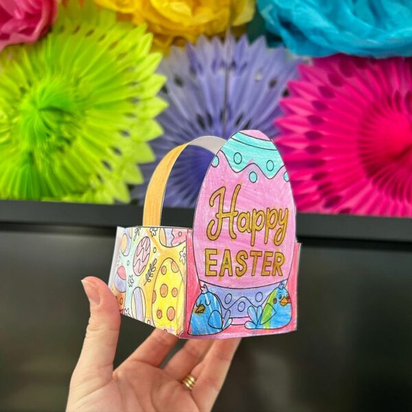 A womans hand holding up a colourful paper Easter egg basket 