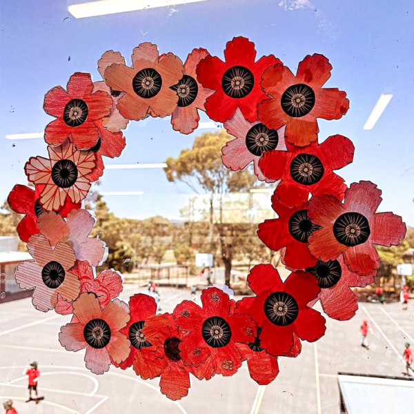 A wreath on a classroom window made of red paper poppies