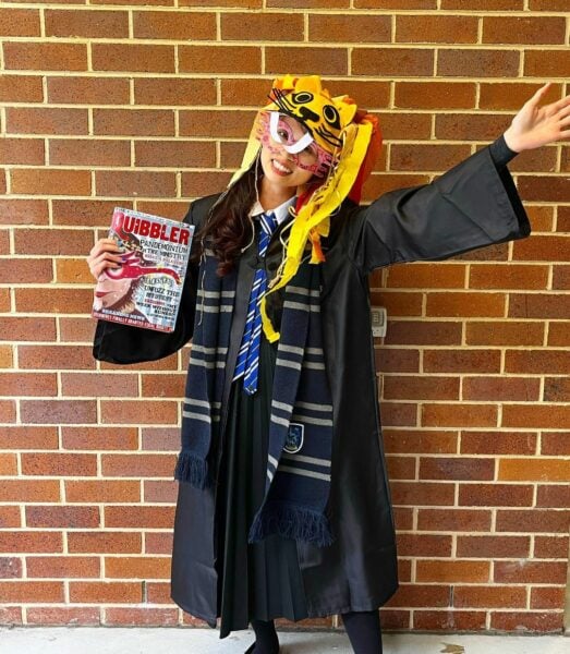 A woman wearing a Harry Potter inspired costume while holding a book called the 